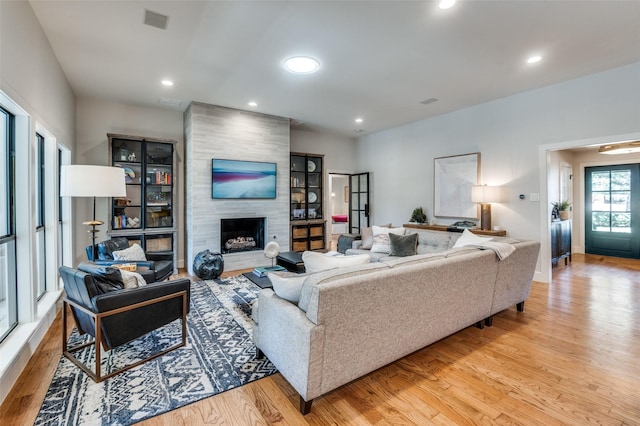 living area featuring visible vents, baseboards, a fireplace, recessed lighting, and light wood-type flooring