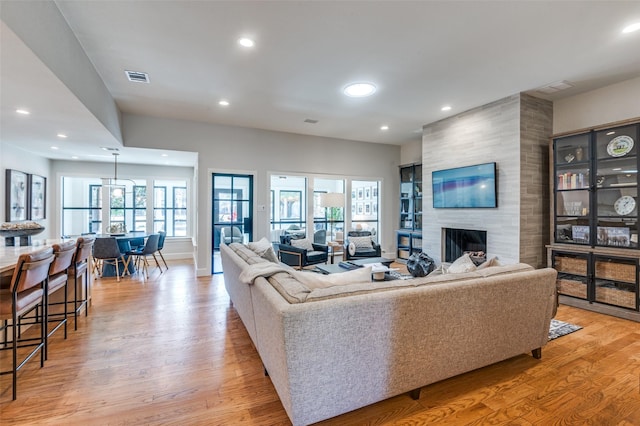 living area with visible vents, recessed lighting, light wood-style floors, baseboards, and a tile fireplace