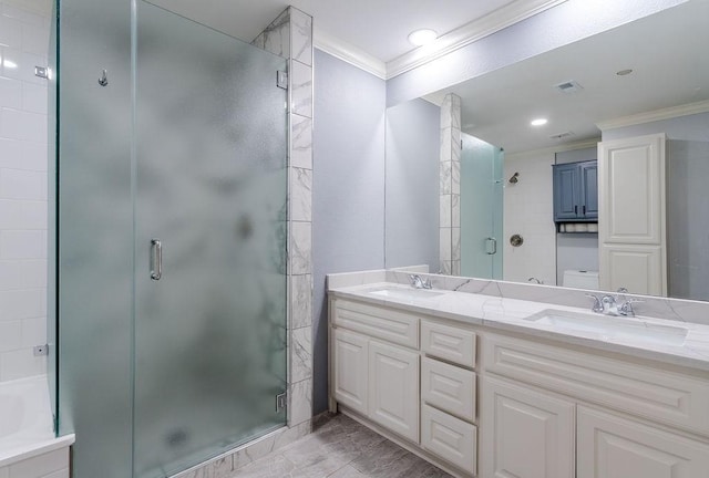 bathroom featuring a sink, double vanity, a shower stall, and crown molding