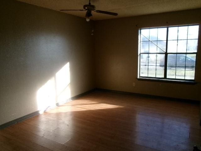 spare room with a ceiling fan, baseboards, and wood finished floors