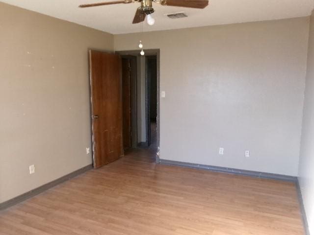 spare room featuring a ceiling fan, light wood-style flooring, baseboards, and visible vents