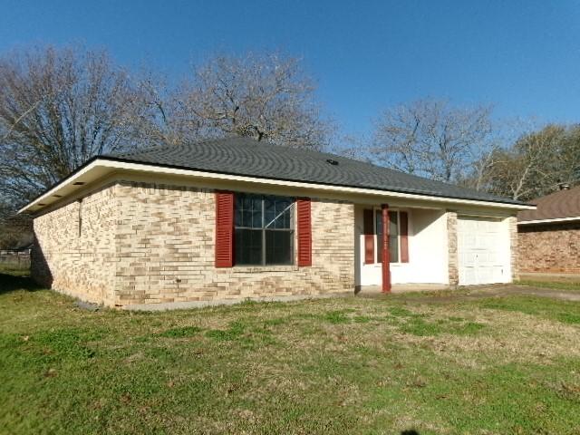 back of house with brick siding, a lawn, and a garage