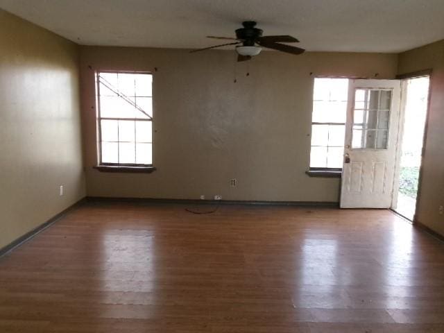 spare room featuring baseboards, wood finished floors, and a ceiling fan