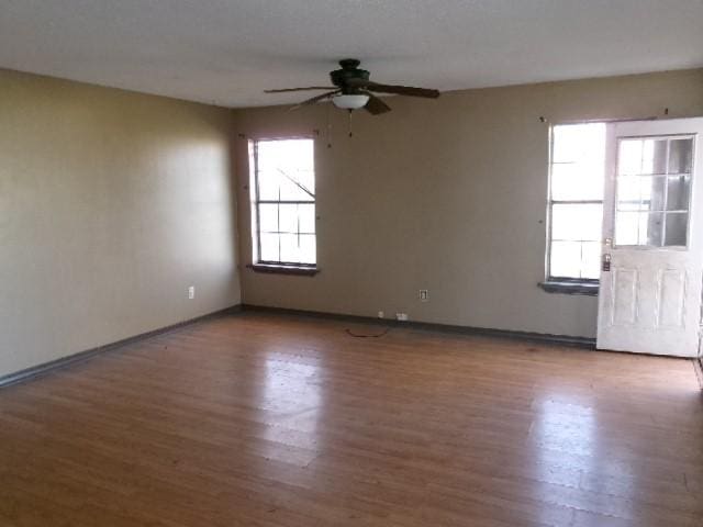 spare room featuring plenty of natural light, wood finished floors, and a ceiling fan