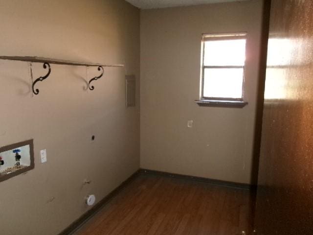 clothes washing area featuring baseboards, washer hookup, electric panel, laundry area, and wood finished floors