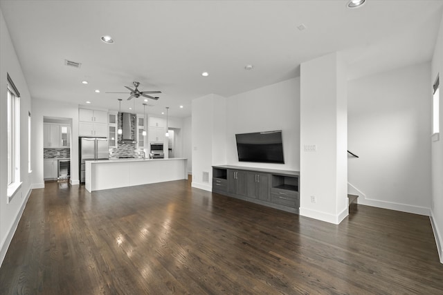 unfurnished living room with a ceiling fan, visible vents, dark wood finished floors, recessed lighting, and stairs