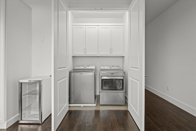 clothes washing area with independent washer and dryer, dark wood finished floors, wine cooler, cabinet space, and baseboards