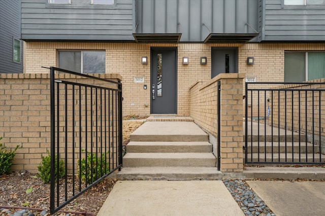 view of exterior entry featuring a gate, brick siding, and fence