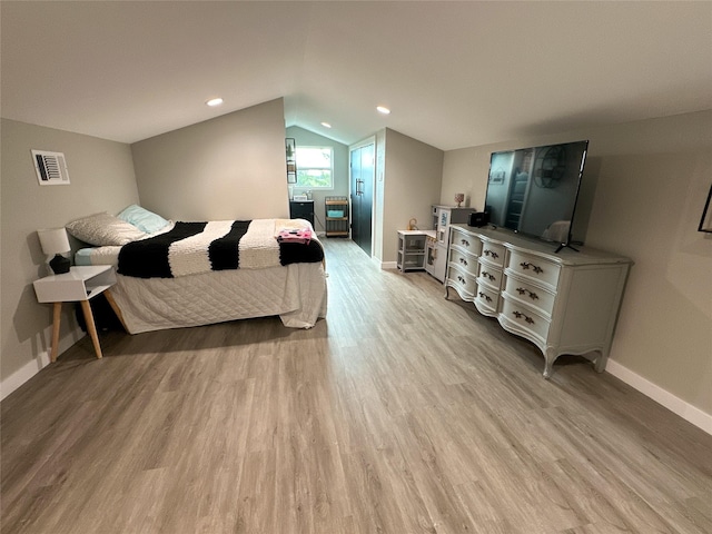 bedroom featuring visible vents, baseboards, light wood-type flooring, and lofted ceiling