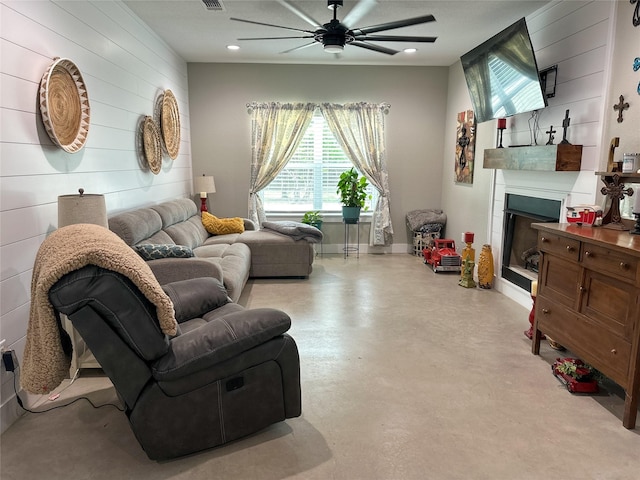 living room featuring visible vents, a fireplace, baseboards, concrete flooring, and ceiling fan