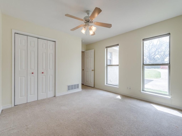 unfurnished bedroom with baseboards, visible vents, light carpet, and a closet