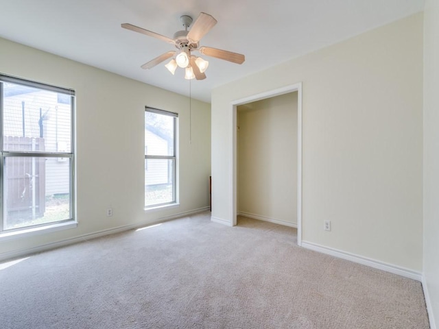 unfurnished bedroom with baseboards, multiple windows, carpet, and a ceiling fan