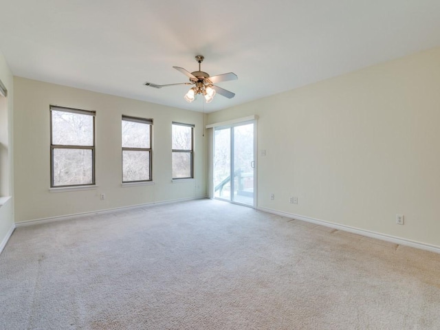 spare room featuring plenty of natural light, a ceiling fan, baseboards, and light carpet