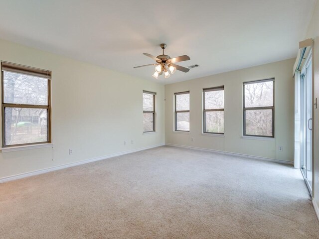 empty room with light carpet, visible vents, a healthy amount of sunlight, and baseboards