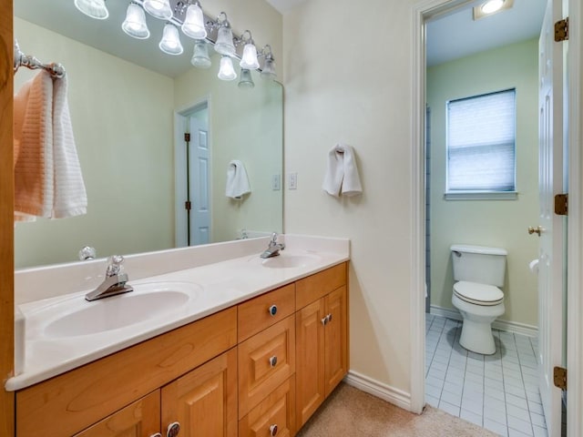 bathroom featuring double vanity, toilet, baseboards, and a sink