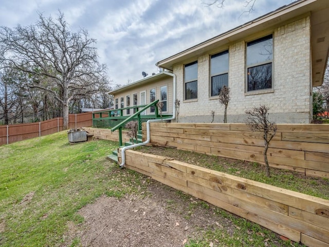 rear view of house with brick siding, a lawn, and fence