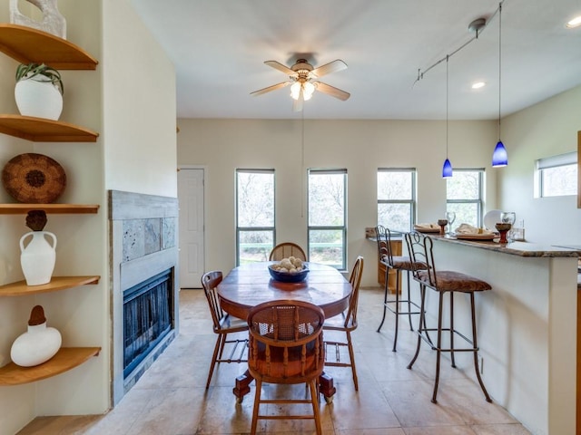 dining space with a ceiling fan, plenty of natural light, a fireplace, and light tile patterned flooring