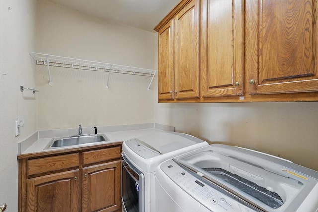 laundry area featuring separate washer and dryer, a sink, and cabinet space