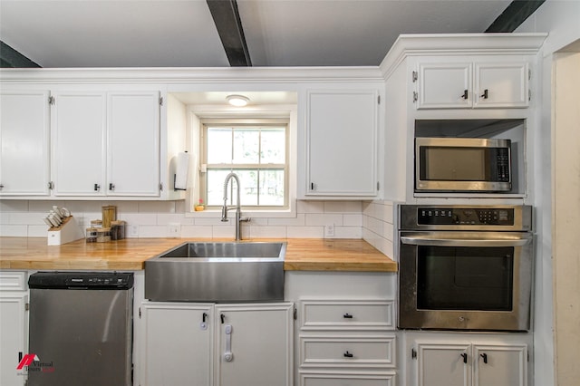 504 Mockingbird Ln, Logansport, LA 71049 - kitchen featuring a sink, decorative backsplash, appliances with stainless steel finishes, wood counters, and white cabinetry