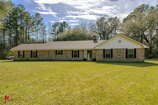 ranch-style house featuring brick siding, a chimney, and a front yard