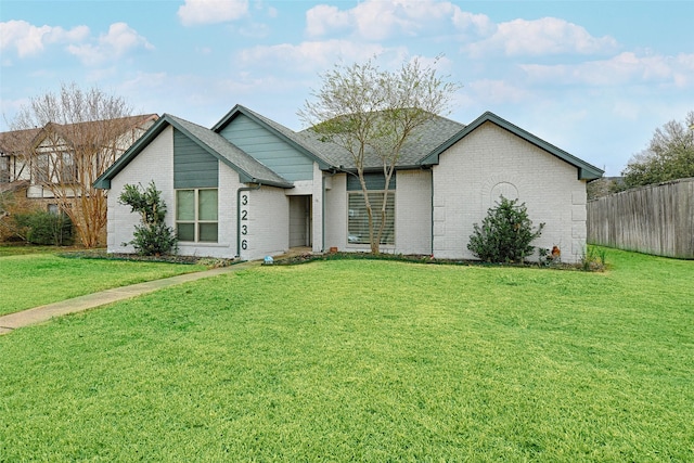 view of front of property featuring a front lawn, fence, and brick siding