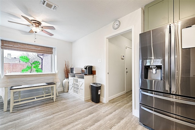 kitchen with a ceiling fan, visible vents, light wood finished floors, baseboards, and stainless steel refrigerator with ice dispenser