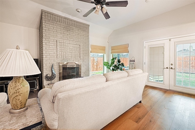 living area featuring plenty of natural light, a brick fireplace, lofted ceiling, and french doors