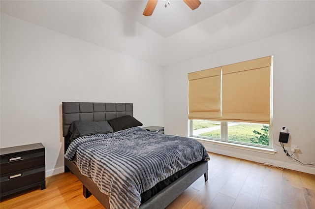 bedroom with light wood-style flooring, a ceiling fan, and baseboards