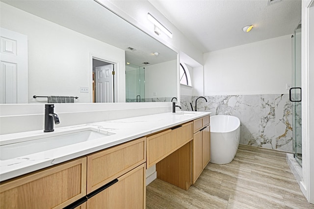 bathroom featuring double vanity, a stall shower, and a sink