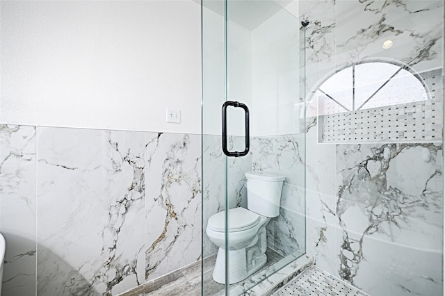 full bath featuring a marble finish shower, toilet, and tile walls