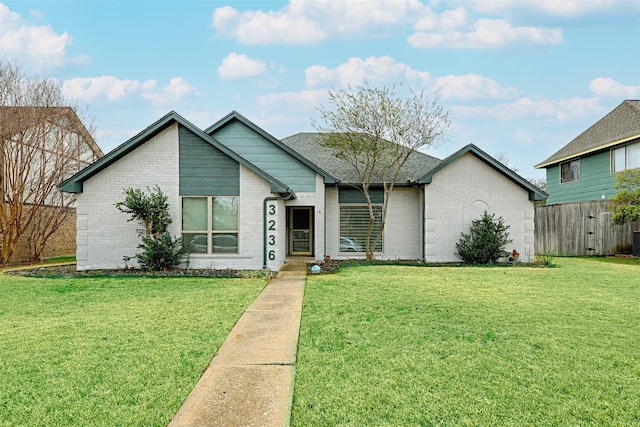 mid-century inspired home with brick siding, a front yard, and a shingled roof