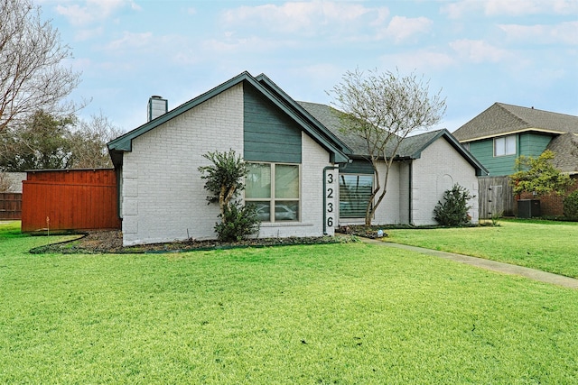 view of front facade with a front yard, fence, a chimney, central air condition unit, and brick siding