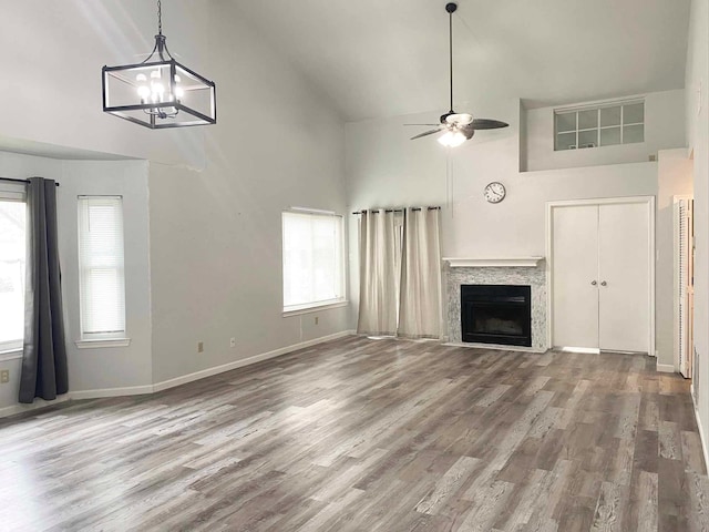 unfurnished living room featuring ceiling fan, high vaulted ceiling, wood finished floors, and a fireplace