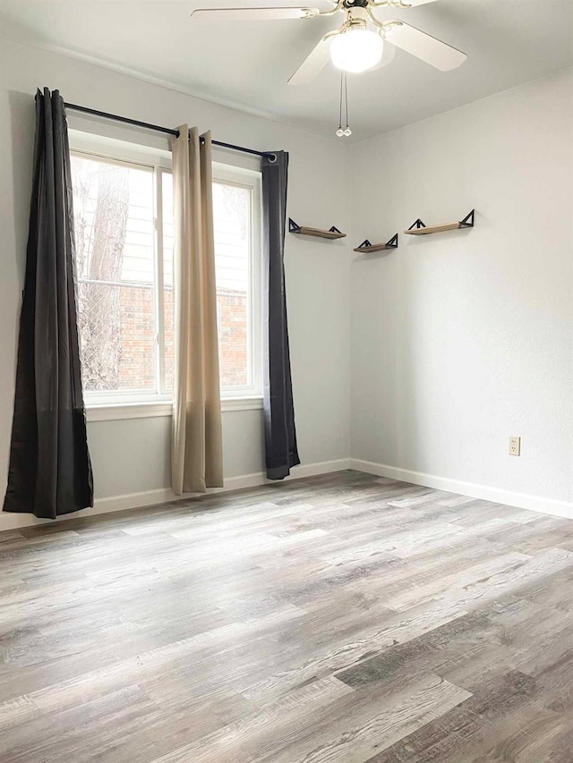 unfurnished room featuring ceiling fan, baseboards, and wood finished floors