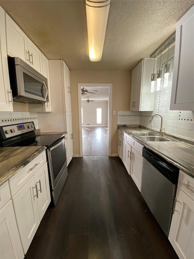 kitchen with dark wood-style flooring, stainless steel appliances, decorative backsplash, and a sink