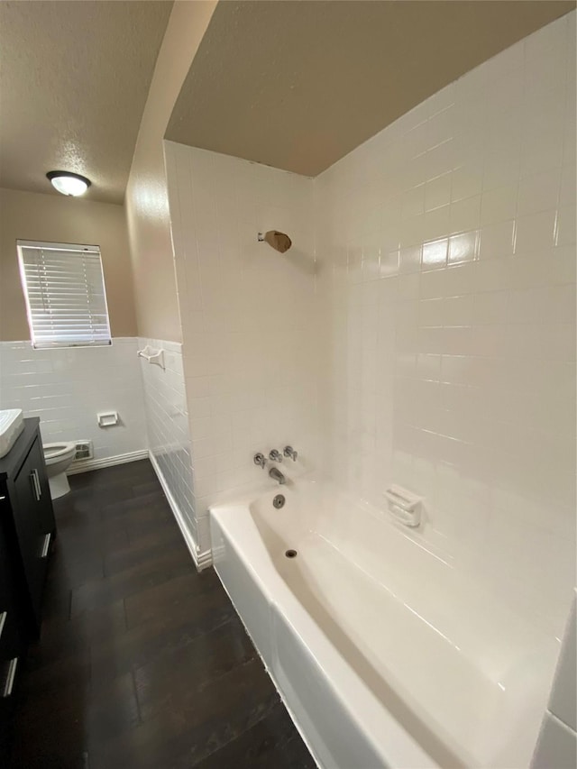 full bathroom featuring toilet, a textured ceiling, wood finished floors, tub / shower combination, and vanity