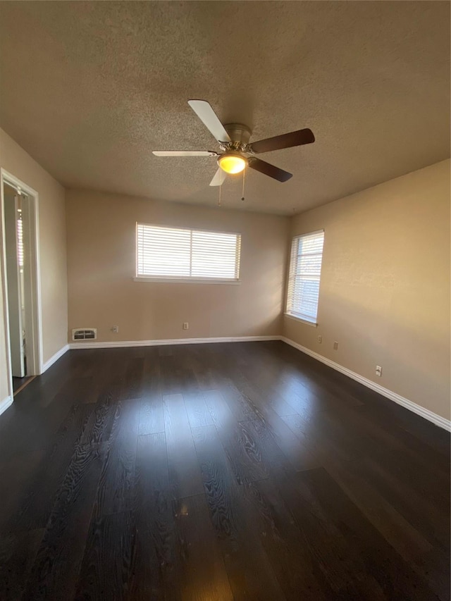 spare room featuring dark wood-style floors, baseboards, and a textured ceiling