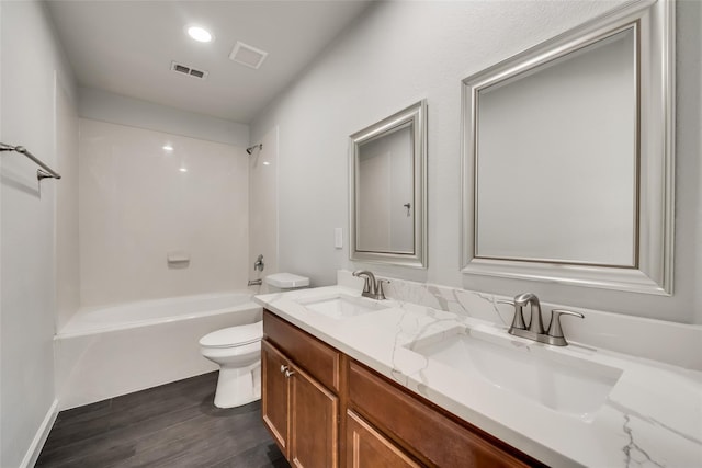 bathroom with toilet, wood finished floors, visible vents, and a sink