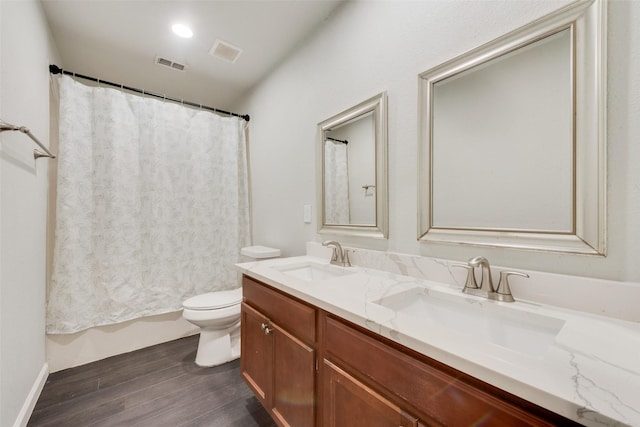 full bathroom featuring visible vents, toilet, a sink, wood finished floors, and double vanity