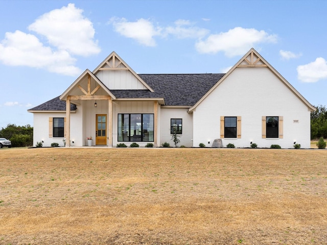 modern farmhouse style home with board and batten siding, a shingled roof, and a front yard