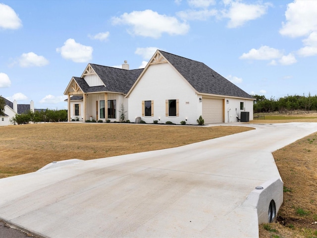 modern inspired farmhouse with a shingled roof, concrete driveway, an attached garage, a front yard, and central AC unit