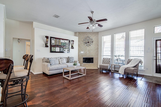 living area featuring a premium fireplace, visible vents, a textured ceiling, and wood finished floors