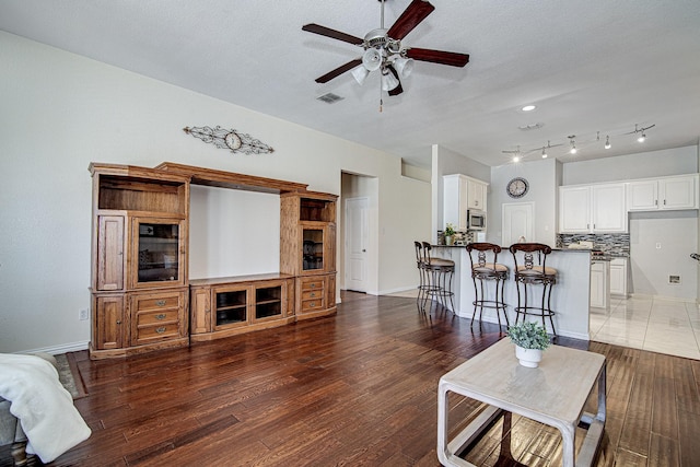 living room with ceiling fan, baseboards, and wood finished floors