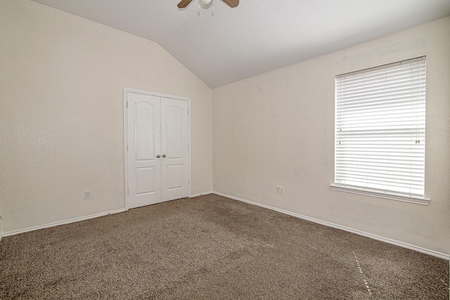 spare room featuring baseboards, lofted ceiling, carpet, and a ceiling fan