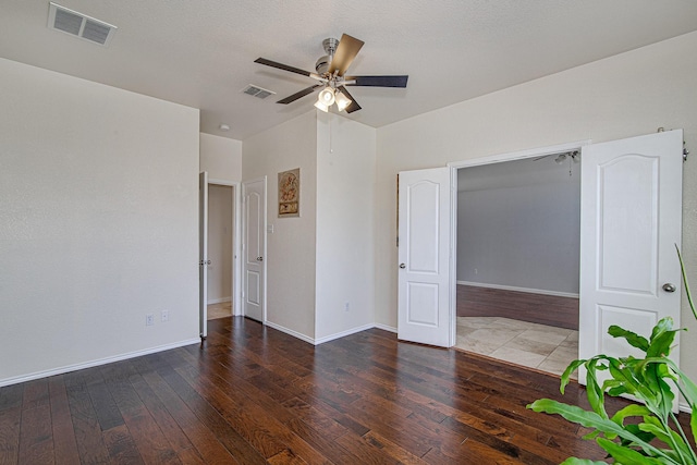 unfurnished room featuring hardwood / wood-style floors, a ceiling fan, visible vents, and baseboards