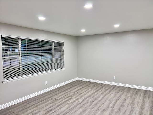 spare room with recessed lighting, wood finished floors, and baseboards