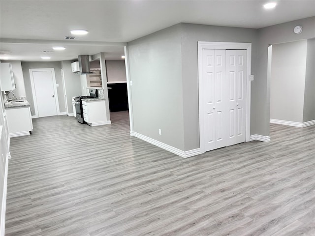 unfurnished living room featuring light wood-style flooring, visible vents, baseboards, and a sink