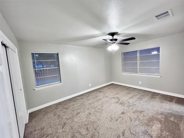 spare room featuring carpet flooring, baseboards, visible vents, and ceiling fan