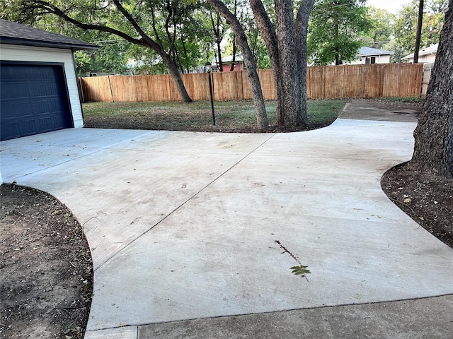 view of patio / terrace featuring fence, a garage, and driveway