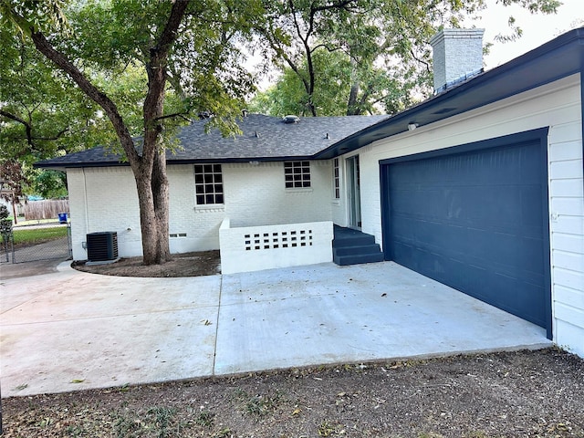 exterior space with concrete driveway, central AC unit, and fence